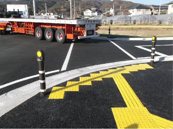 交差点の巻き込み部に沿って設置されたフレキシブル側溝と点字ブロック