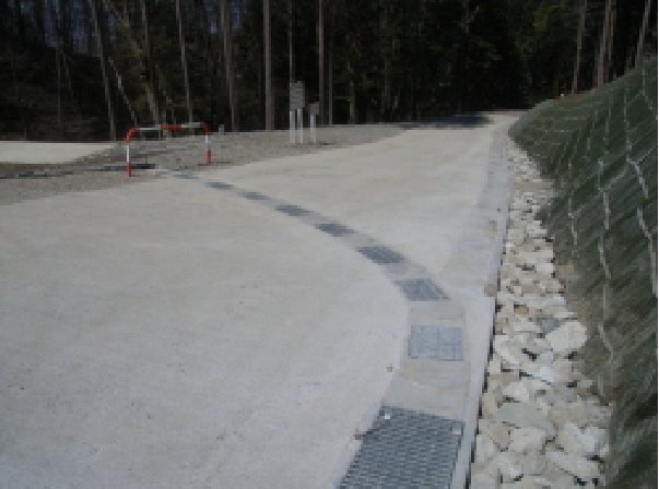 山間部の道路脇に緩い曲線で設置されたフレキシブル側溝